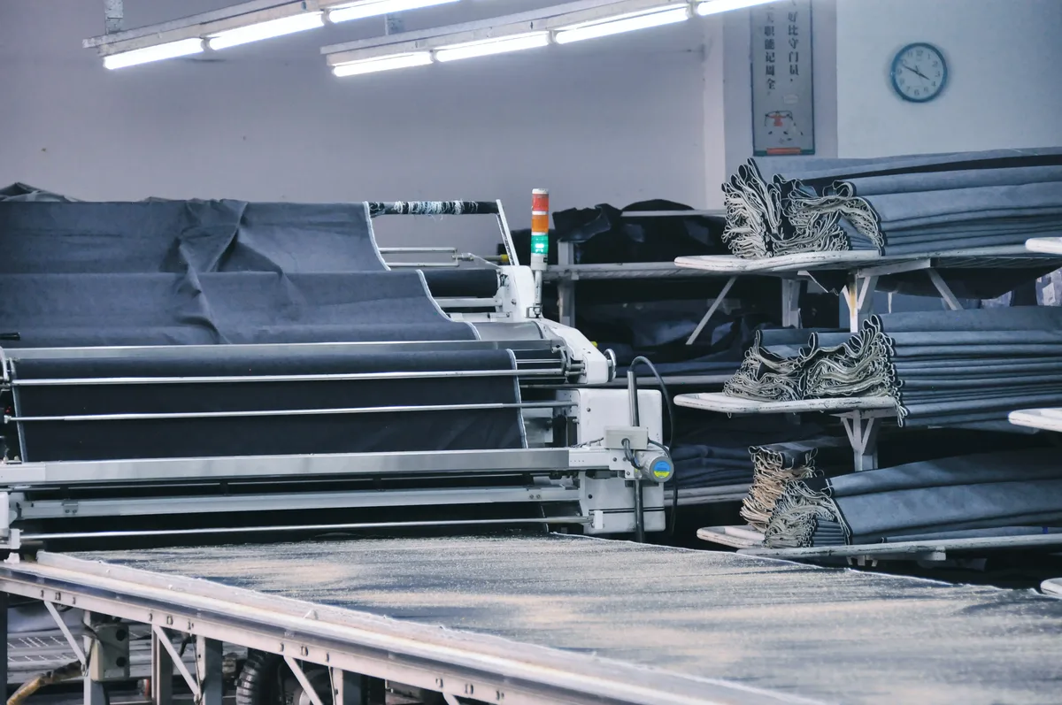 Industrial fabric cutting machine spreading multiple layers of denim fabric on the factory production floor