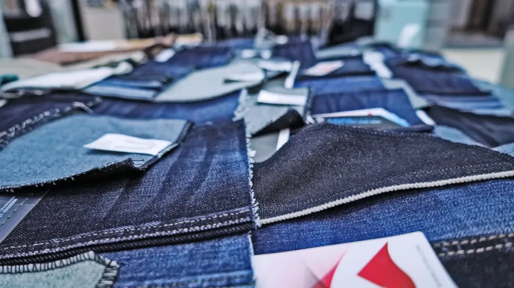Various denim fabric swatches displayed on a sample table comparing different weights from lightweight to heavyweight for sourcing decisions