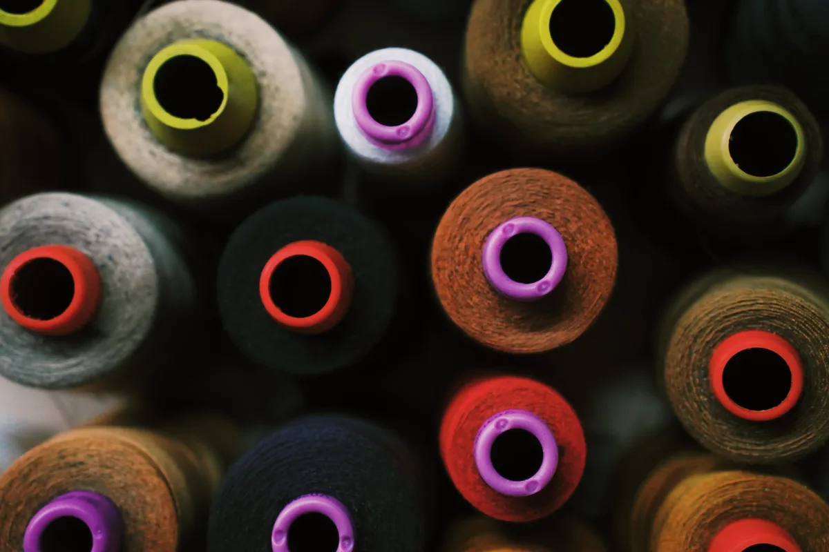 Colorful premium cotton thread spools arranged closely showing variety of yarn colors available for luxury denim production