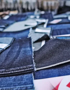 Various denim fabric swatches displayed on a sample table comparing different weights from lightweight to heavyweight for sourcing decisions