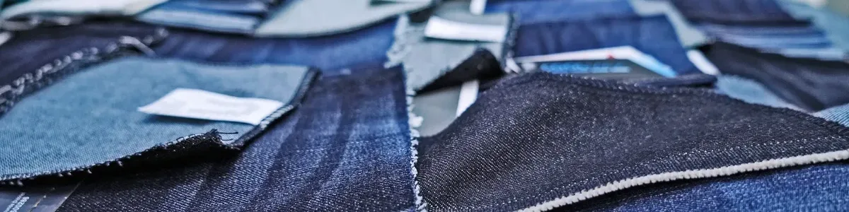Various denim fabric swatches displayed on a sample table comparing different weights from lightweight to heavyweight for sourcing decisions
